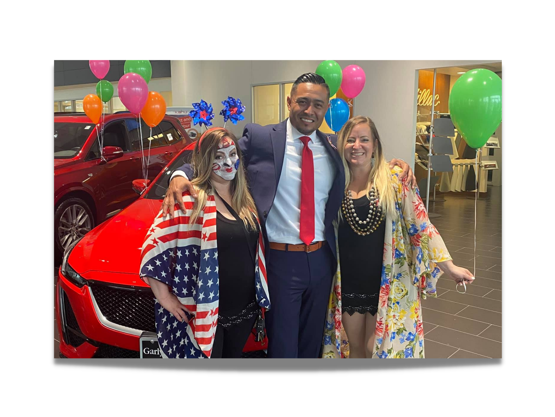 Freedom & Fireworks Celebration at car dealership with people posing in festive attire and balloons