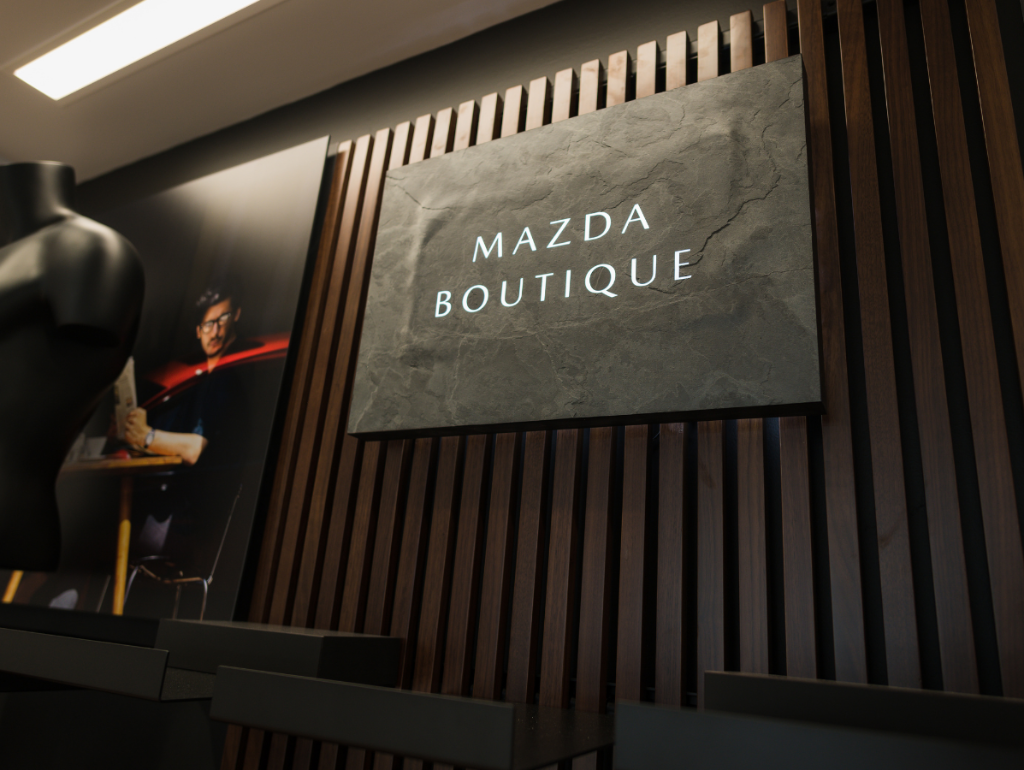 Mazda Boutique signage on dark wooden slat wall with mannequin display